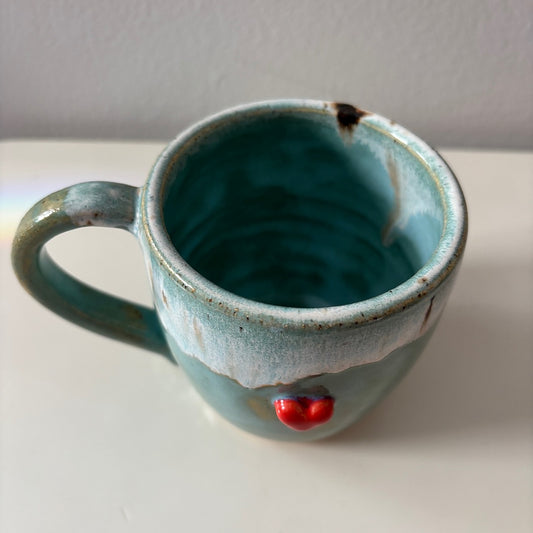 Blue ceramic mug with a sweet red heart on a white surface