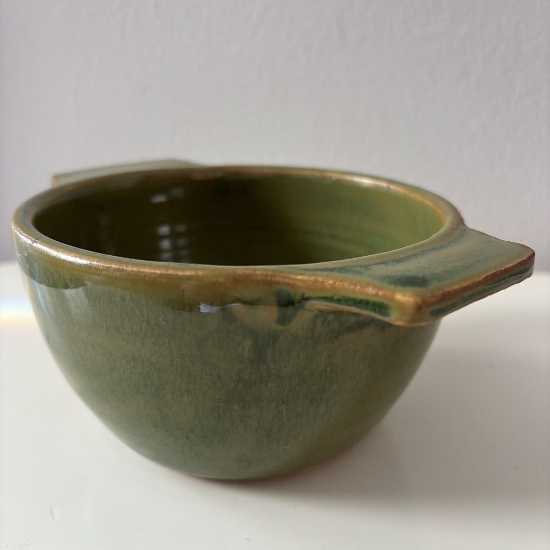 Green ceramic berry bowl on a white surface