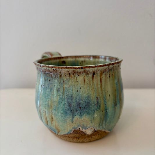 Turquoise green and speckled handmade ceramic mug on a light background