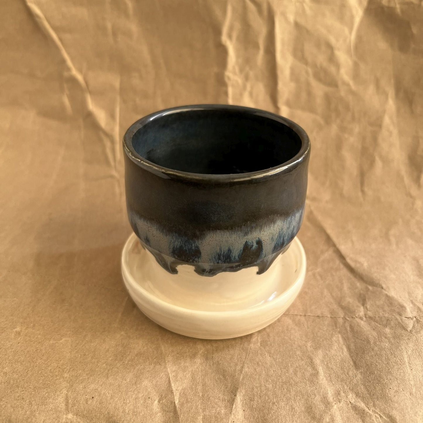 Midnight blue and white small handmade ceramic planter with integrated saucer on a crumpled brown paper background