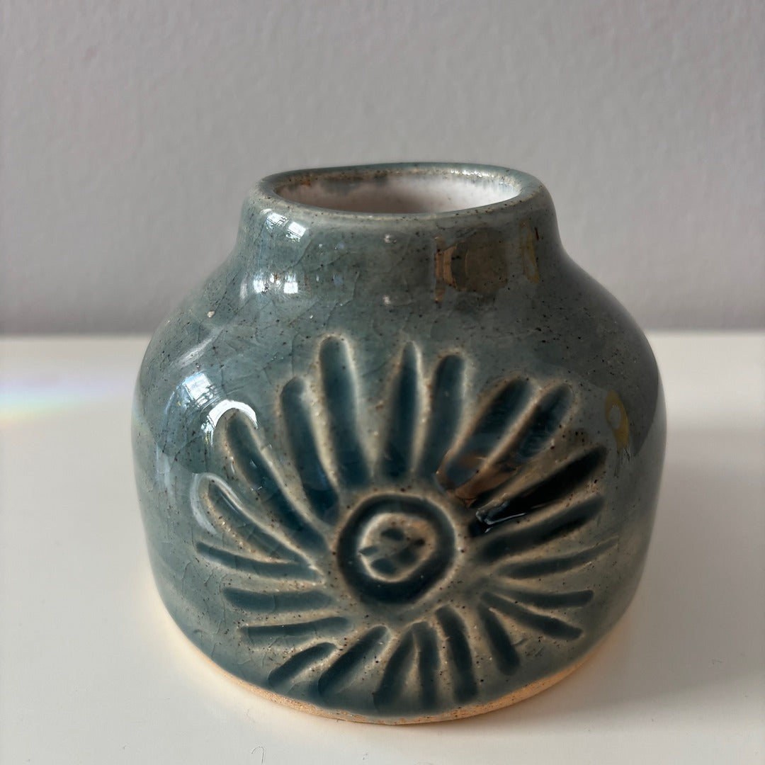 Blue ceramic vase with sunburst carving on a neutral background