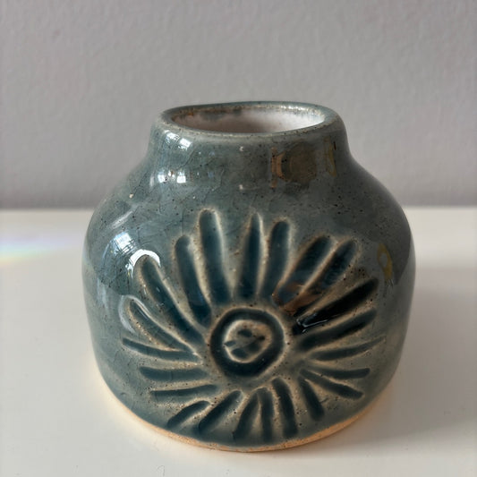 Blue ceramic vase with sunburst carving on a neutral background