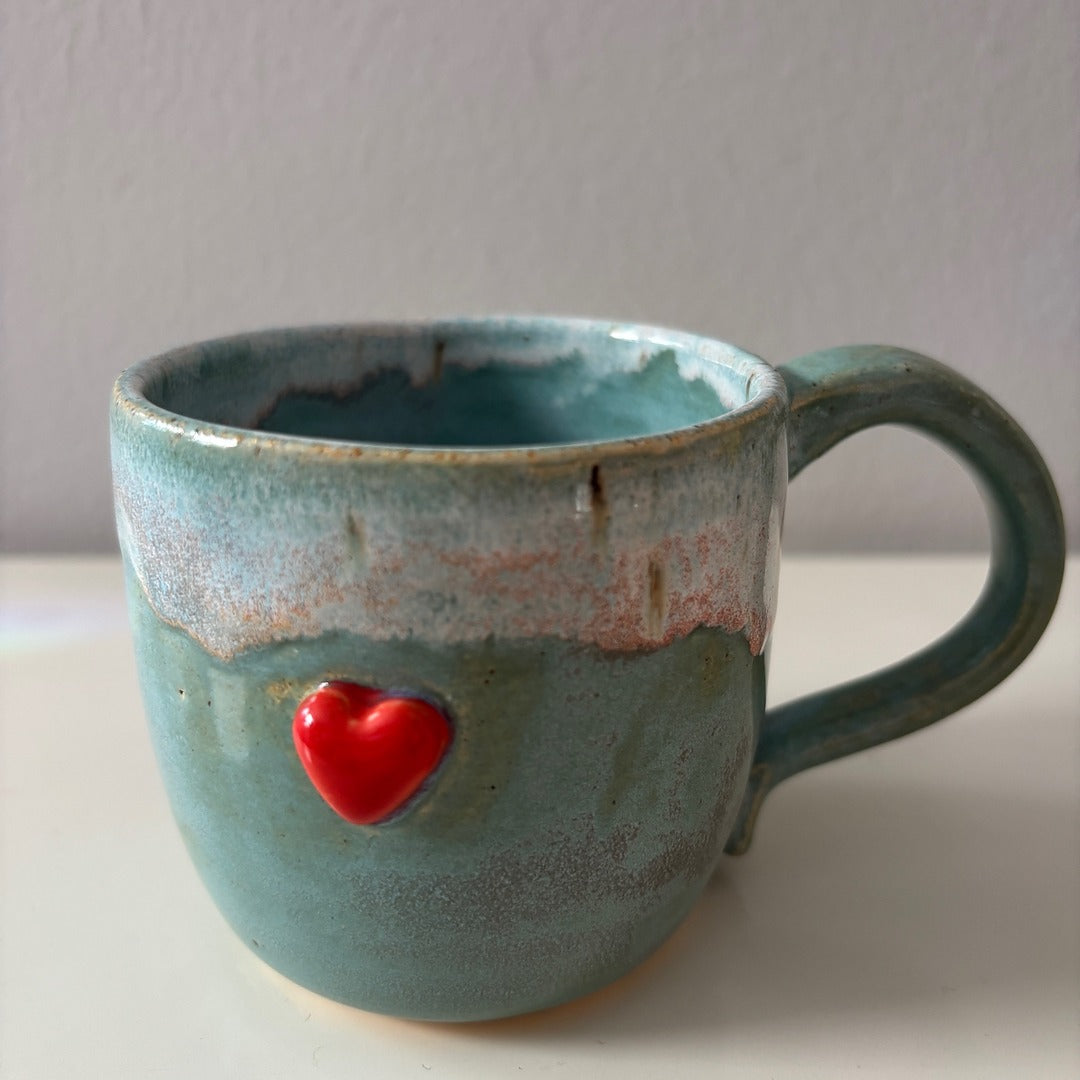 Blue ceramic mug with a sweet red heart on a white surface