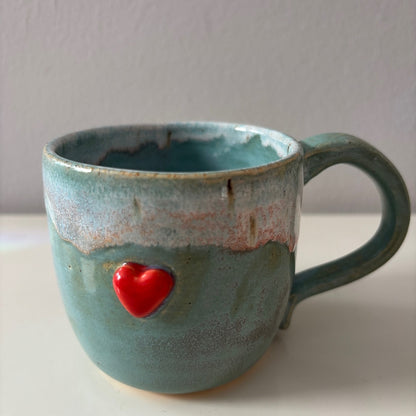 Blue ceramic mug with a sweet red heart on a white surface