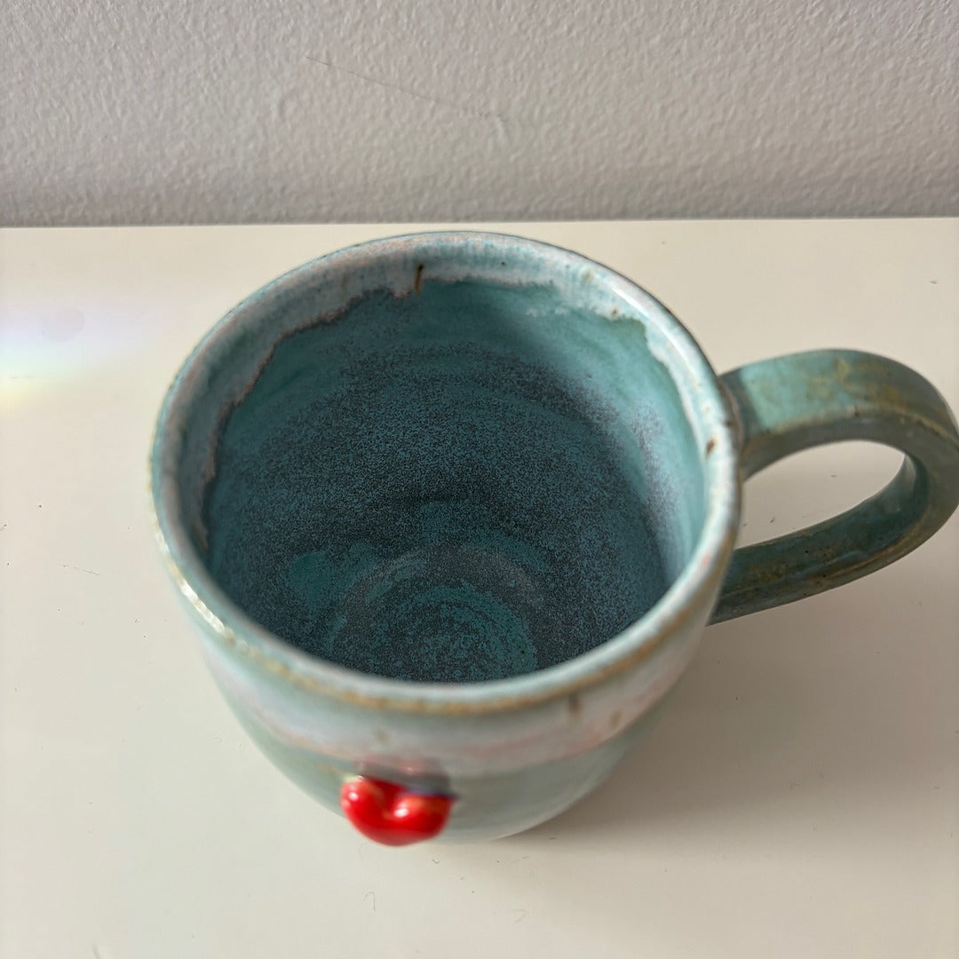 Blue ceramic mug with a sweet red heart on a white surface