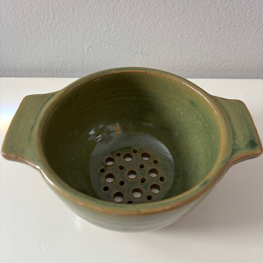 Green ceramic berry bowl on a white surface