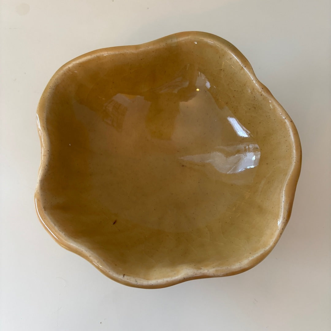 Honey colored scalloped ceramic bowl on a light background