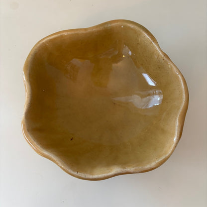 Honey colored scalloped ceramic bowl on a light background