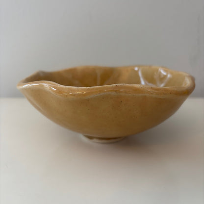 Honey colored scalloped ceramic bowl on a light background
