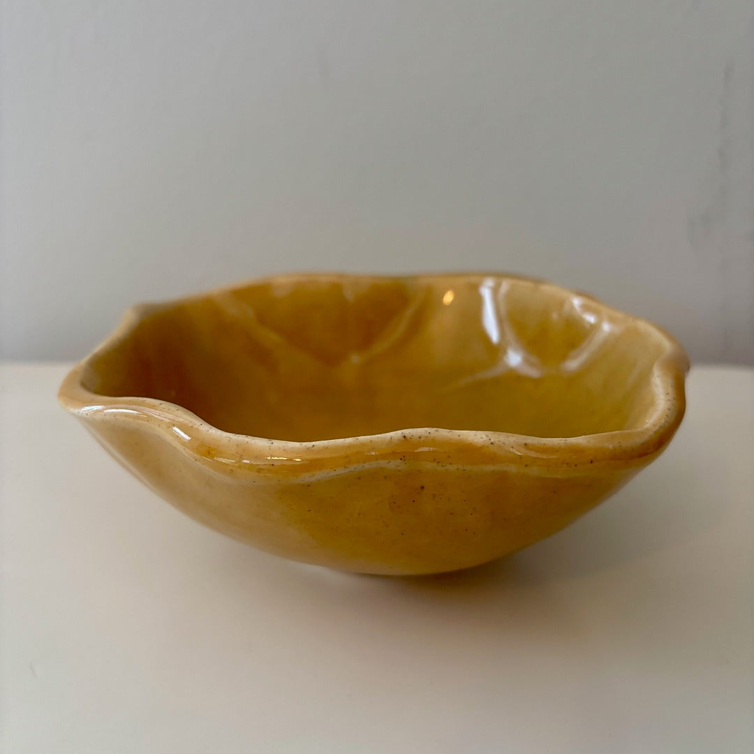 Honey colored scalloped ceramic bowl on a light background