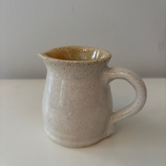 Handmade ceramic speckled white pitcher on a light background