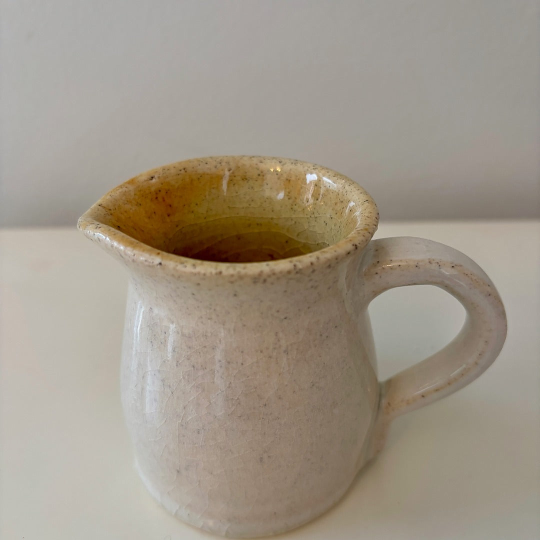 Handmade ceramic speckled white pitcher on a light background
