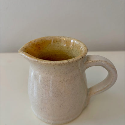 Handmade ceramic speckled white pitcher on a light background