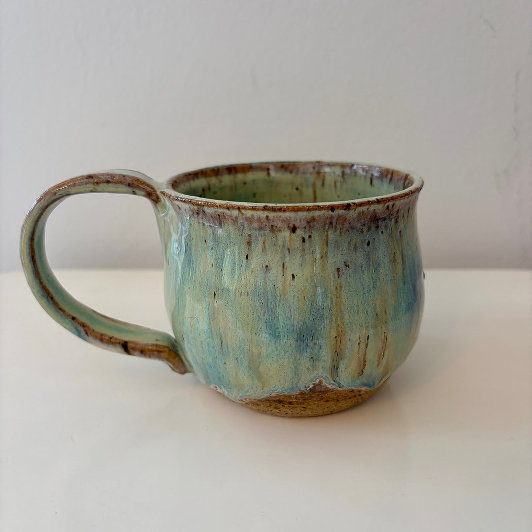 Turquoise green and speckled handmade ceramic mug on a light background