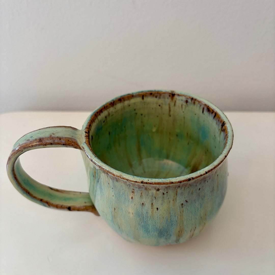 Turquoise green and speckled handmade ceramic mug on a light background