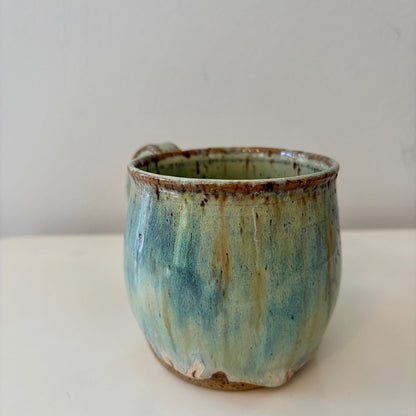 Turquoise green and speckled handmade ceramic mug on a light background