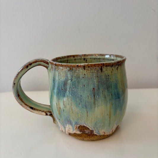 Turquoise green and speckled handmade ceramic mug on a light background