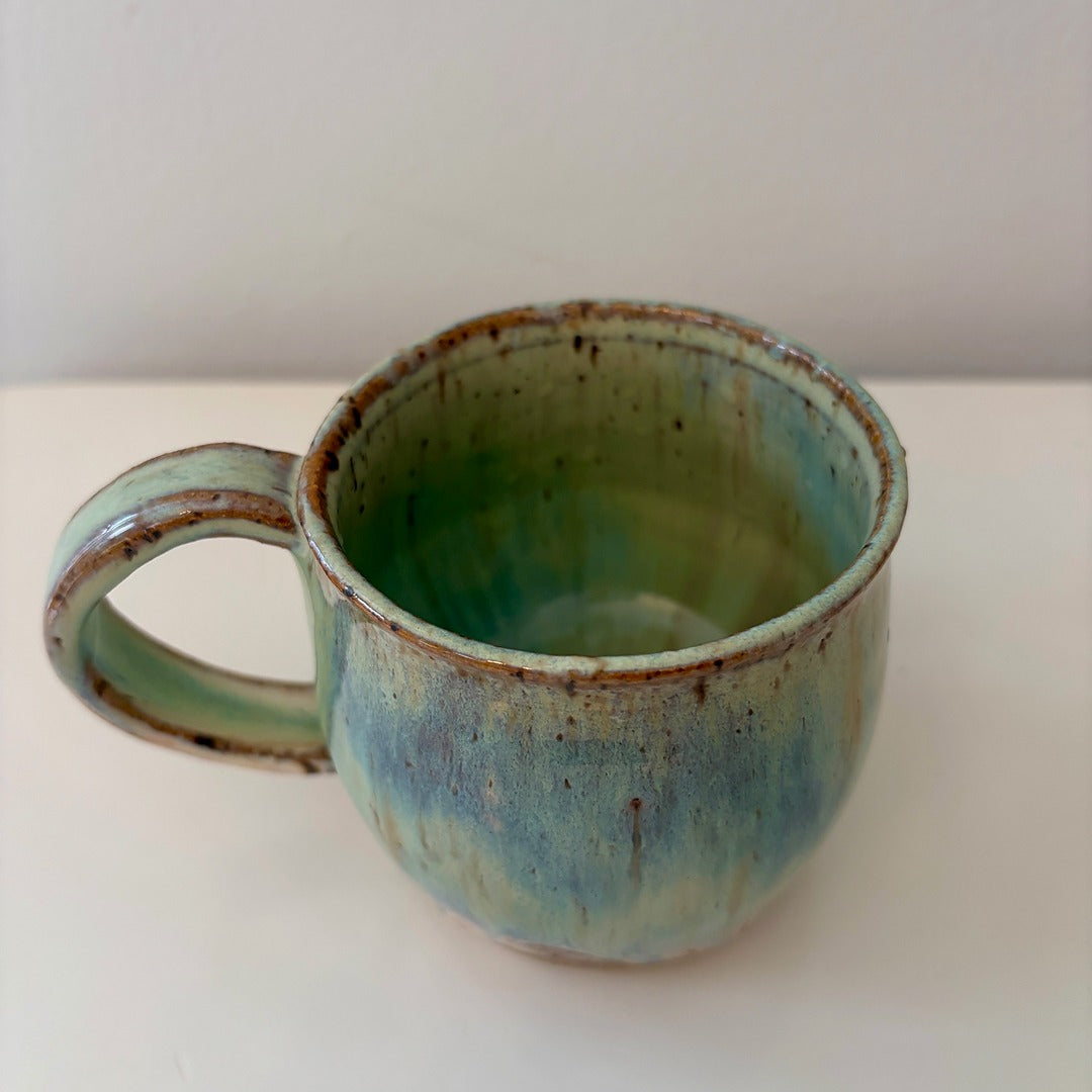 Turquoise green and speckled handmade ceramic mug on a light background