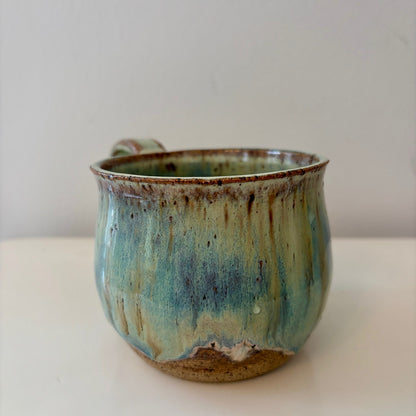 Turquoise green and speckled handmade ceramic mug on a light background