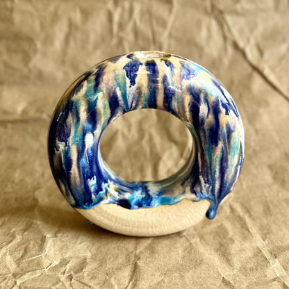 Ceramic donut vase with blue and white glaze on a crumpled brown paper background