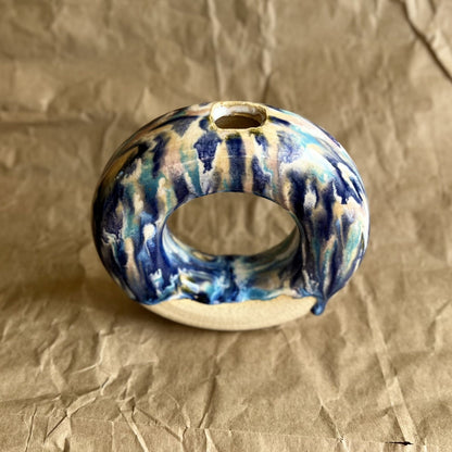 Ceramic donut vase with blue and white glaze on a crumpled brown paper background