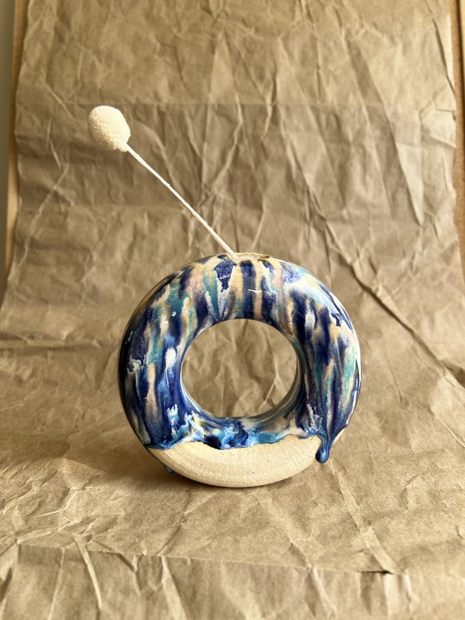 Ceramic donut vase with blue and white glaze on a crumpled brown paper background