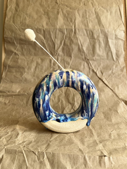 Ceramic donut vase with blue and white glaze on a crumpled brown paper background