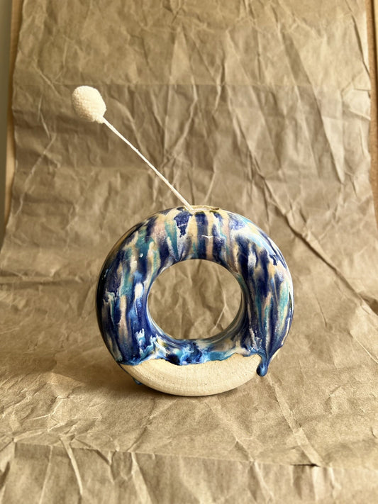 Ceramic donut vase with blue and white glaze on a crumpled brown paper background