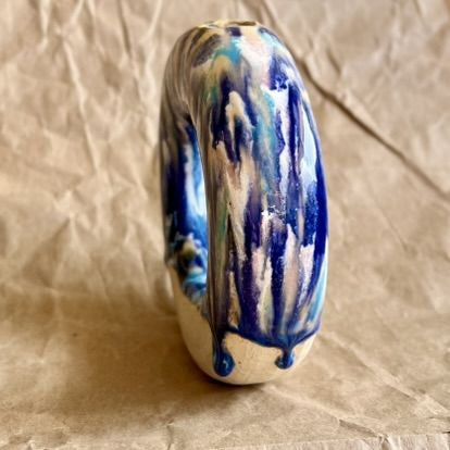 Handmade ceramic donut vase with blue and white glaze on a crumpled brown paper background