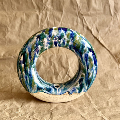 Handmade ceramic donut vase with blue and green glaze on a brown paper background