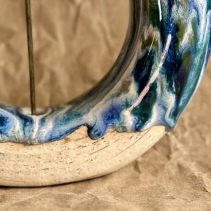 Handmade ceramic donut vase with blue and green glaze on a brown paper background