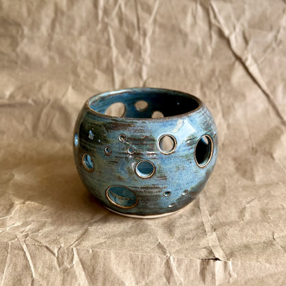 Blue ceramic votive with circular patterns on a brown textured background