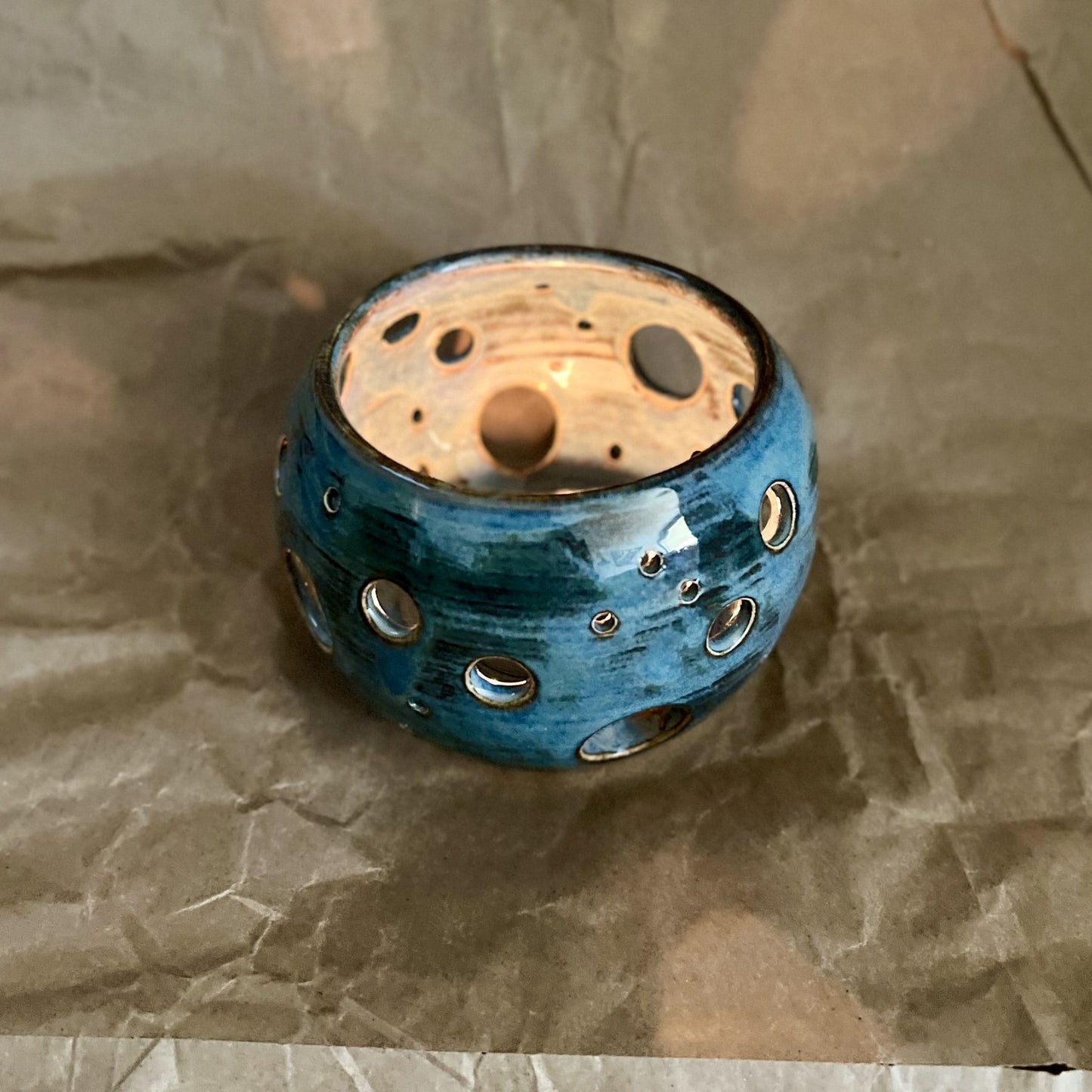 indigo blue ceramic votive with circle cutouts on brown paper surface