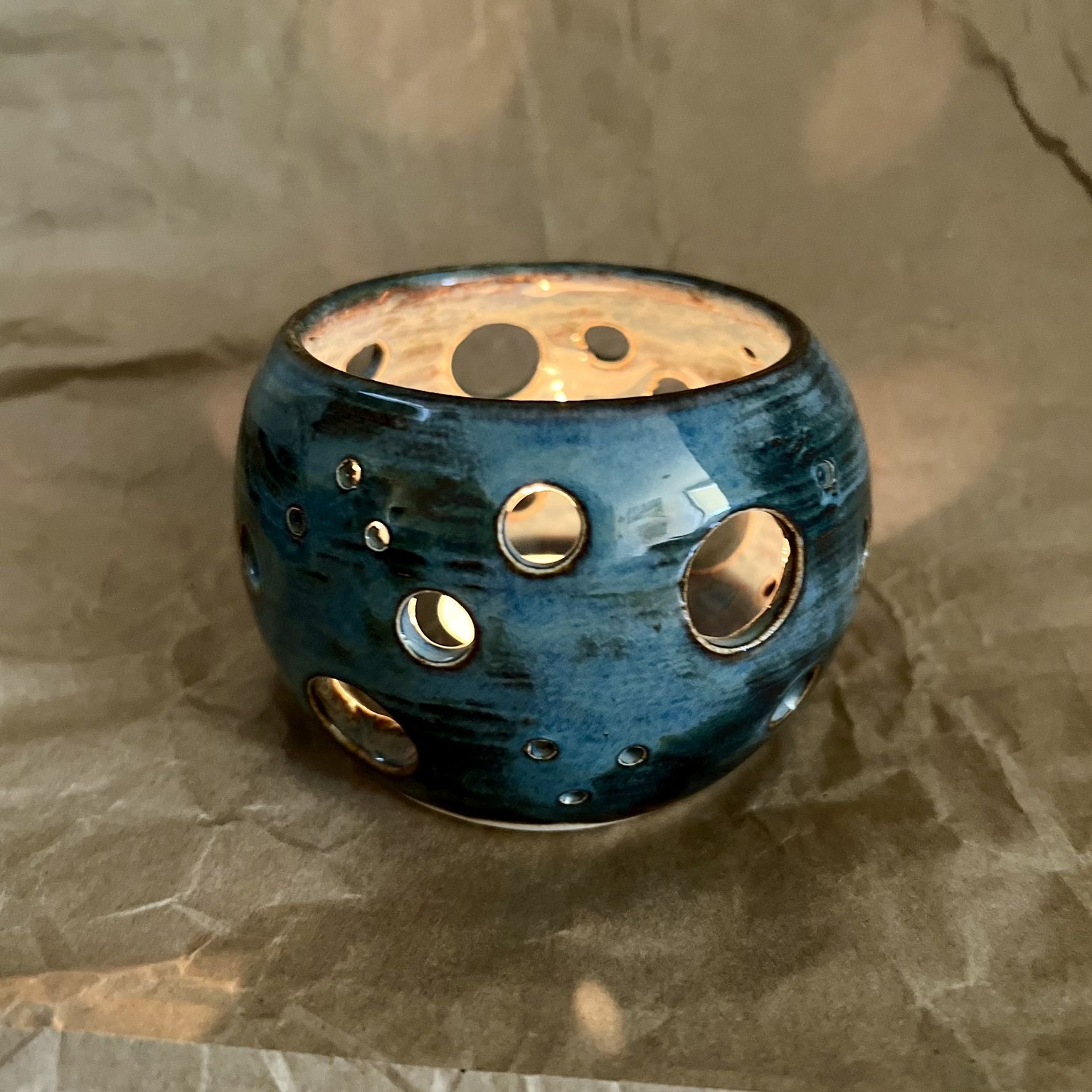 indigo blue ceramic votive with circle cutouts on brown paper surface