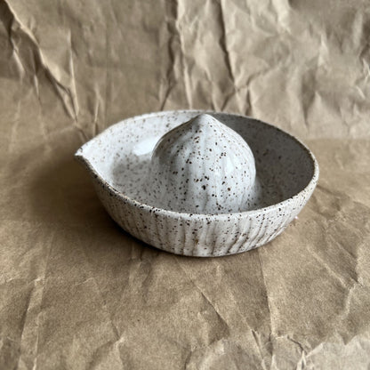 Speckled ceramic juicer on crumpled brown paper