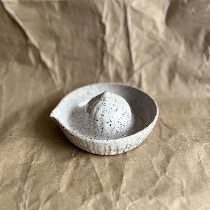 Speckled ceramic juicer on a textured brown background
