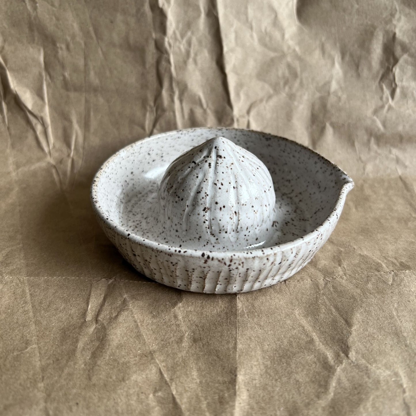 Speckled ceramic juicer on a brown paper background