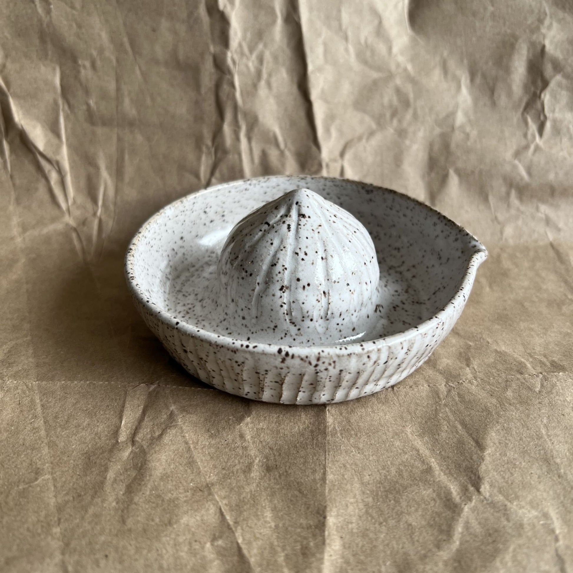 Speckled ceramic juicer on a brown paper background