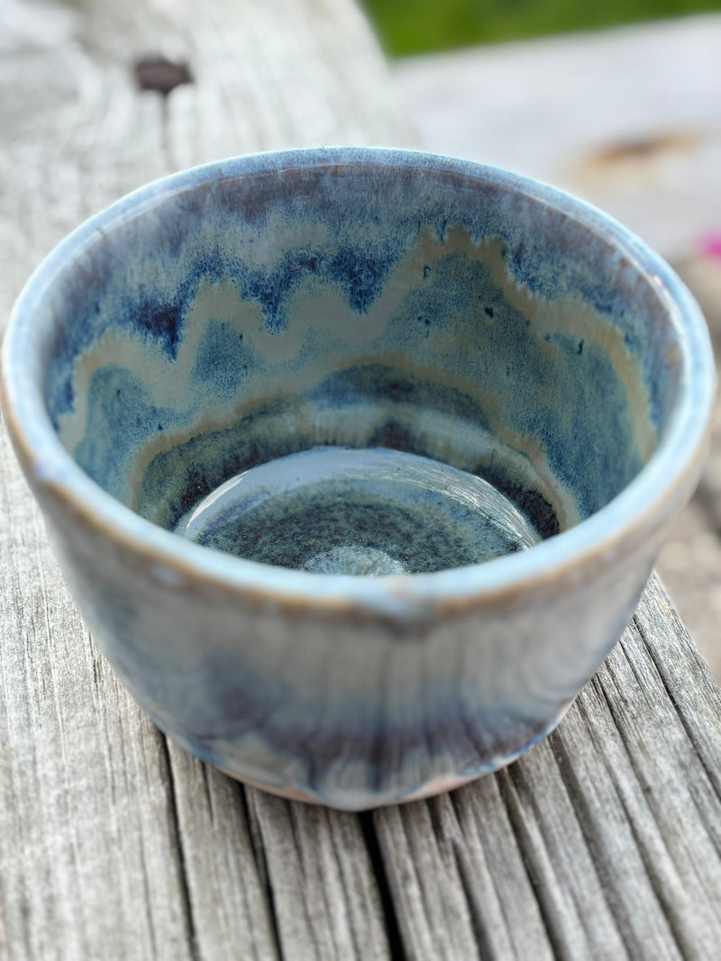 Blue ceramic espresso cup with wavy pattern on a wooden surface