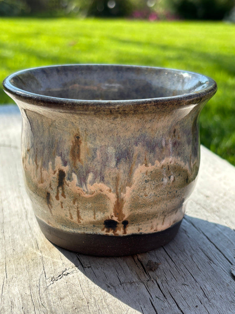 Ceramic cup with a reactive blue glaze on a wooden surface