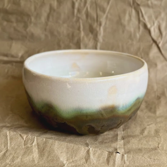 Pearl and walnut color bowl on a brown paper background with a beam of light crossing the bowl.