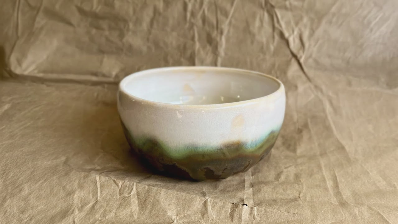 Pearl and walnut color bowl on a brown paper background with a beam of light crossing the bowl.