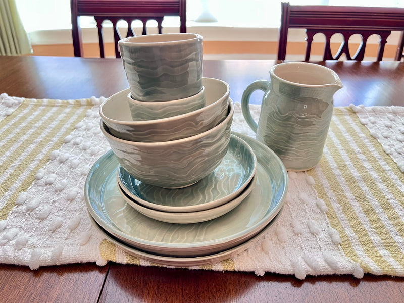 Set of ceramic dinnerware on a table with a striped placemat
