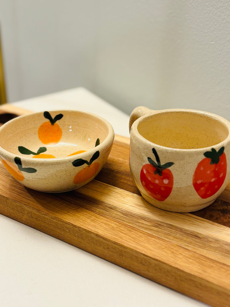 Two ceramic bowls with fruit designs on a wooden tray.